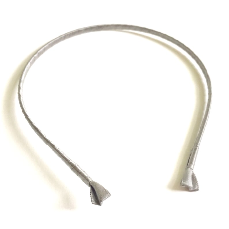 May include: A silver headband with a simple design. The headband is made of a soft, flexible material and is perfect for everyday wear.