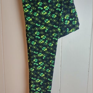May include: Black leggings with a green and yellow four-leaf clover pattern.