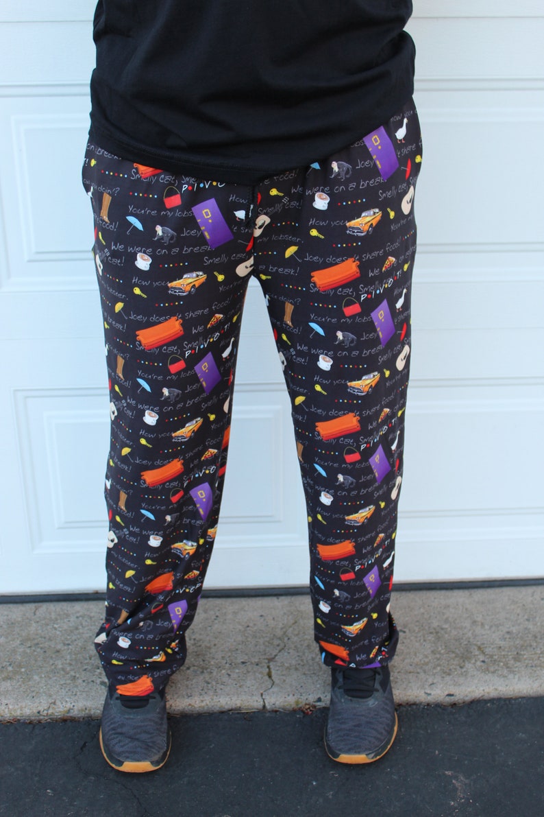 May include: Black pajama pants with a repeating pattern of text and images from the TV show "Friends". The text includes phrases like "Smelly Cat", "We were on a break", and "Joey doesn't share food".