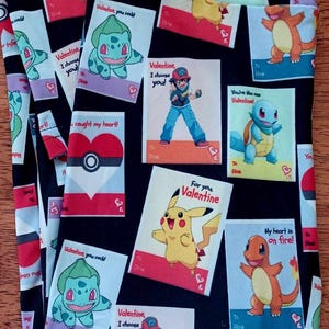 May include: Black leggings with a repeating pattern of colourful Valentine's Day cards featuring Pokemon characters. The cards have messages like "Valentine, I choose you!" and "You're the one Valentine!"