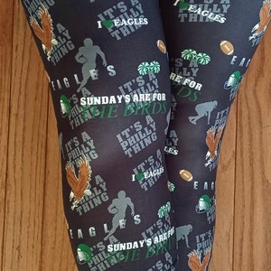 Könnte beinhalten: Schwarze Leggings mit einem sich wiederholenden Muster aus grünem und weißem Text, der "It's a Philly thing" und "Sunday's are for the Birds" lautet. Die Leggings haben auch ein sich wiederholendes Muster aus grünen und weißen Footballhelmen, Cheerleadern und Adlern.