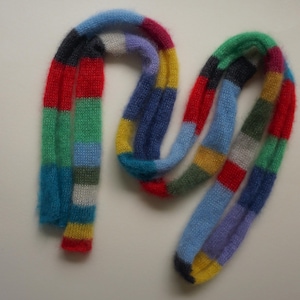 May include: A colourful striped knitted scarf with a variety of colours including red, blue, green, yellow, and white.