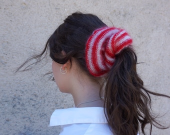 May include: A woman with long brown hair wearing a white button-down shirt and a red and white striped knit hair scrunchie.