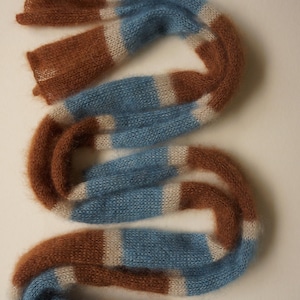 May include: A brown, white and blue striped scarf made of soft, fuzzy yarn.