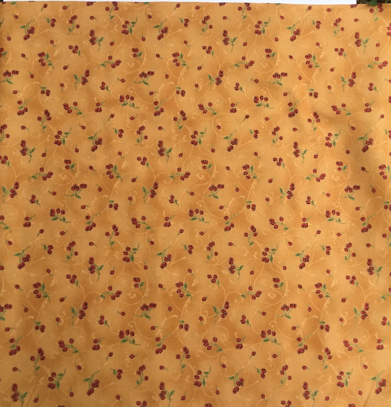 in stock and ready to ship! Red berries with green stems outlined in gold woven quilters cotton sold as yardage