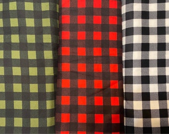 May include: Three fabric swatches with different plaid patterns. The first swatch is a green and black plaid, the second is a red and black plaid, and the third is a black and white plaid.