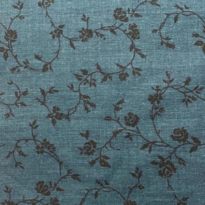 May include: A teal blue fabric with a repeating pattern of black floral vines. The vines have small, simple flower shapes.