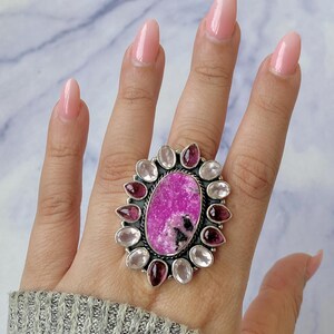 May include: A silver ring with a large pink and white oval gemstone surrounded by smaller pink and white gemstones.