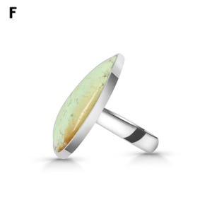 May include: A silver ring featuring a large, oval-shaped, pale green stone with tan inclusions. The stone is set in a smooth, polished silver bezel, and the ring band is made of a plain, solid silver metal. The letter F is visible in the corner.