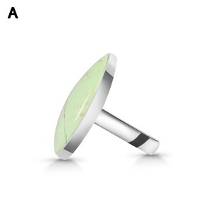 May include: A silver ring featuring a large, oval-shaped, light green stone with subtle white veining. The stone is set in a smooth, polished silver bezel, and the band is a simple, solid silver shank. The letter A is visible in the top left corner.