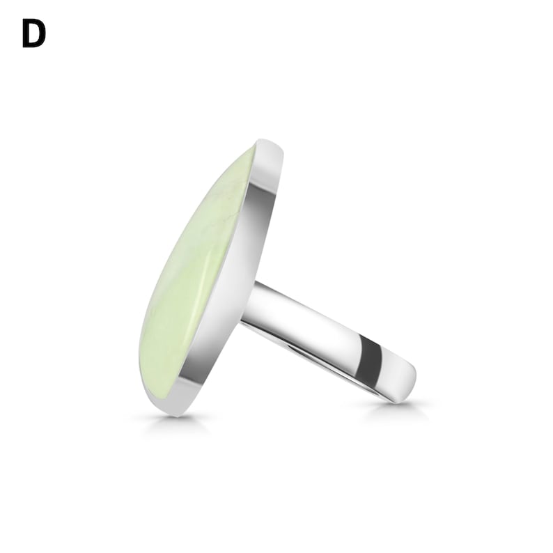 May include: A silver-toned ring featuring a smooth, pale green, teardrop-shaped stone set in a polished metal bezel. The letter D is visible in the upper left corner. The ring is shown from a side profile angle, highlighting the band and setting.