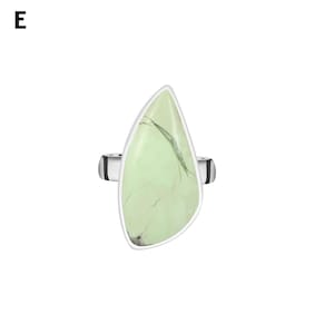 May include: A silver ring featuring a large, teardrop-shaped, pale green stone with dark, thin, vein-like inclusions. The stone is set in a smooth silver bezel, and the band is visible on both sides of the setting. The letter E is in the top left.