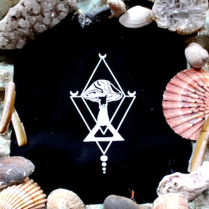 Könnte beinhalten: Ein schwarzes Quadrat mit einem weißen geometrischen Pilzdesign, umgeben von Muscheln, Kristallen und Steinen. Das Design beinhaltet einen Pilz in einer Raute, mit Monden und einem Dreieck.