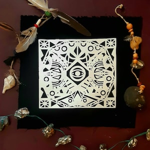 Könnte beinhalten: Ein geometrisches Design in Schwarzweiß mit einem zentralen Augenmotiv. Das Design ist auf weißem Hintergrund gedruckt und mit einem schwarzen Rahmen versehen.