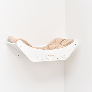 May include: White corner cat bed with a beige cushion. The bed is labeled "Kitty" and "Cats Mode".