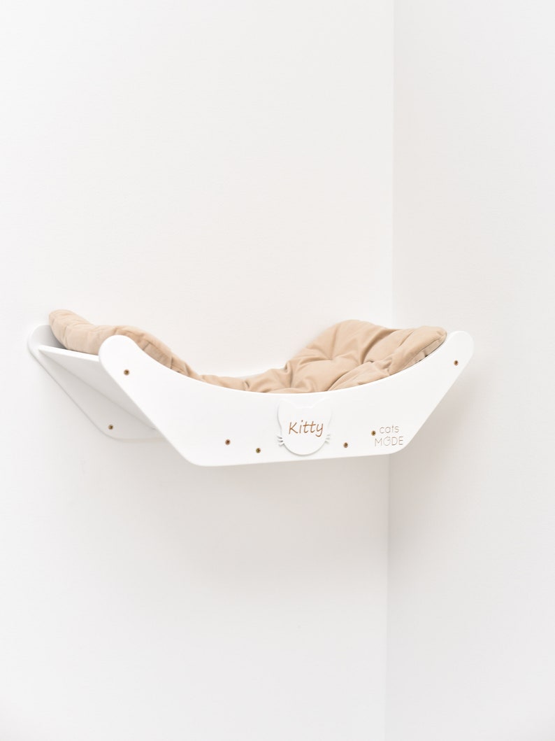 May include: White corner cat bed with a beige cushion. The bed is labeled "Kitty" and "Cats Mode".