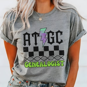 May include: Gray t-shirt with a graphic design featuring a lightning bolt, the letters ATGC, a checkered pattern, and the text "Genealogist".