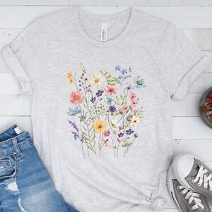 May include: A heather grey t-shirt with a floral print featuring a variety of colorful flowers, including pink, yellow, blue, and purple.