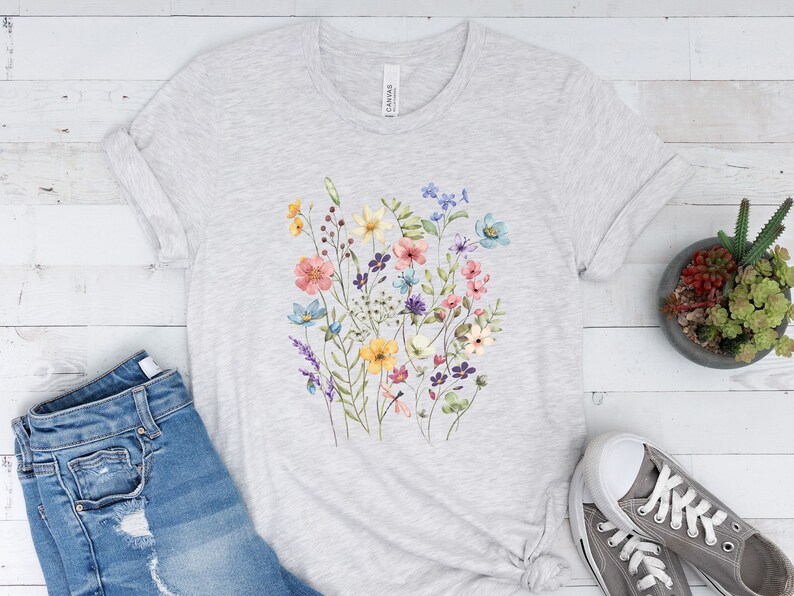 May include: A heather grey t-shirt with a floral print featuring a variety of colorful flowers, including pink, yellow, blue, and purple.