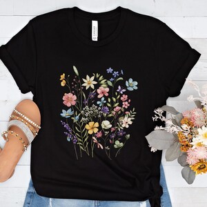 May include: Black t-shirt with a colorful floral print featuring pink, yellow, blue, and green flowers.