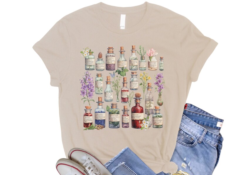 May include: A beige t-shirt with a vintage illustration of various glass bottles filled with colorful liquids and surrounded by flowers and herbs.