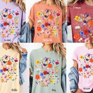 May include: Six different colored t-shirts with a floral print design. The colors are orchid, terracotta, crimson, butter, gray, and blossom.