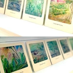May include: A collection of six framed watercolor paintings, each featuring a different nature scene. The paintings are displayed on a white shelf. The paintings are all signed "Copyright by Ro."
