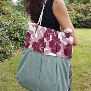 Può includere: Una grande borsa tote verde e bianca con una stampa floreale. La borsa ha un manico in corda bianca e una fodera in tessuto verde.