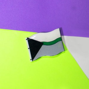 May include: A green, white, and black flag with a wavy design. The flag is on a green and purple background.