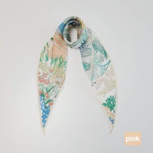 May include: A patterned silk scarf with a botanical design in pink, blue, green, and cream. The scarf displays a detailed illustration of flowers, leaves, and a decorative pot. The word "pink" is printed in a pink box.