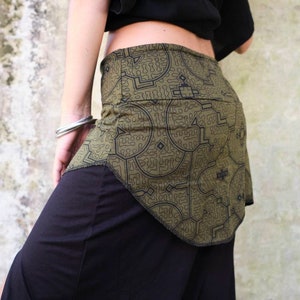 Puede incluir: Una falda verde con un patrón geométrico en blanco y negro. La falda tiene un diseño asimétrico único y está hecha de una tela ligera.