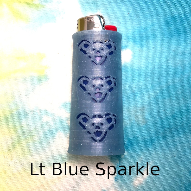 May include: A light blue lighter with a sparkle finish and a design of three bears on the side.  The lighter is labeled "Lt Blue Sparkle".