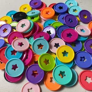 May include: A collection of colorful, round disc-shaped planner accessories. The discs are in various bright colors, including pink, blue, green, yellow, orange, and purple. Each disc has a star-shaped cutout in the center.