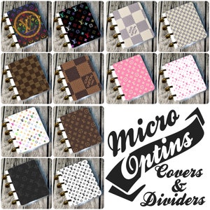Może przedstawiać: Kolekcja okładek i przegródek Micro Optins, prezentująca różne wzory. Okładki zdobią wzory kratki, monogramy i nadruki z logo w kolorach brązowym, różowym, czarnym i białym. Okładki są oprawione złotymi pierścieniami.