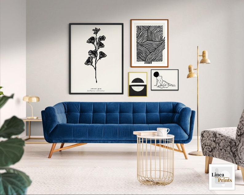 May include: A blue velvet sofa with a gold metal side table and three black and white framed prints on the wall. The prints feature a floral design, abstract lines, and a figure.