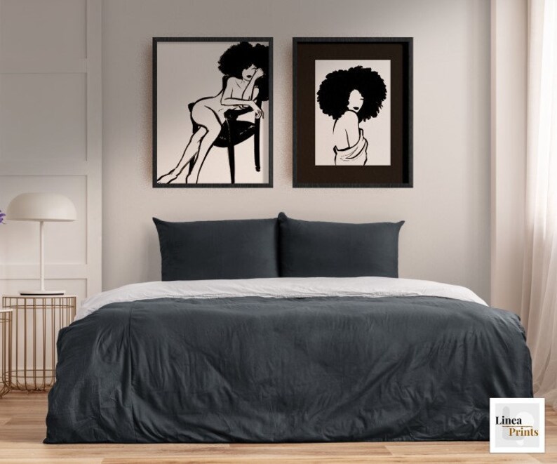 Pu&ograve; includere: Due stampe in bianco e nero di donne con acconciature afro, realizzate con linee. Le stampe sono incorniciate con cornici nere e sono appese a un muro bianco sopra un letto grigio.