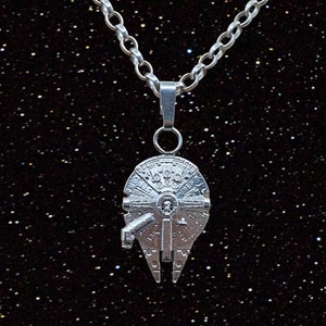 May include: A silver necklace featuring a detailed pendant shaped like the Millennium Falcon spaceship from Star Wars.