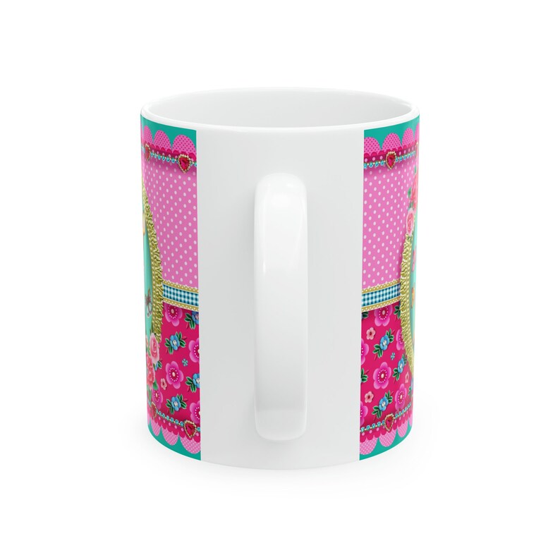 May include: White ceramic mug with a pink, blue, and green floral pattern. The pattern includes polka dots, stripes, and floral designs.