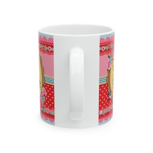 May include: White ceramic mug with a colorful design featuring pink, red, blue, and white polka dots, hearts, and floral patterns. The design includes a vintage-style frame with a bird and floral accents.