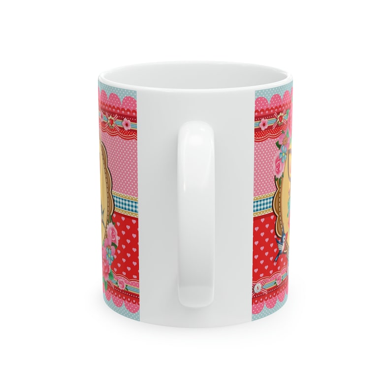 May include: White ceramic mug with a colorful design featuring pink, red, blue, and white polka dots, hearts, and floral patterns. The design includes a vintage-style frame with a bird and floral accents.