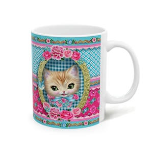 May include: White ceramic mug with a colorful design featuring a kitten with blue eyes, pink flowers, and a blue bird. The background is a patchwork of blue and pink gingham patterns.