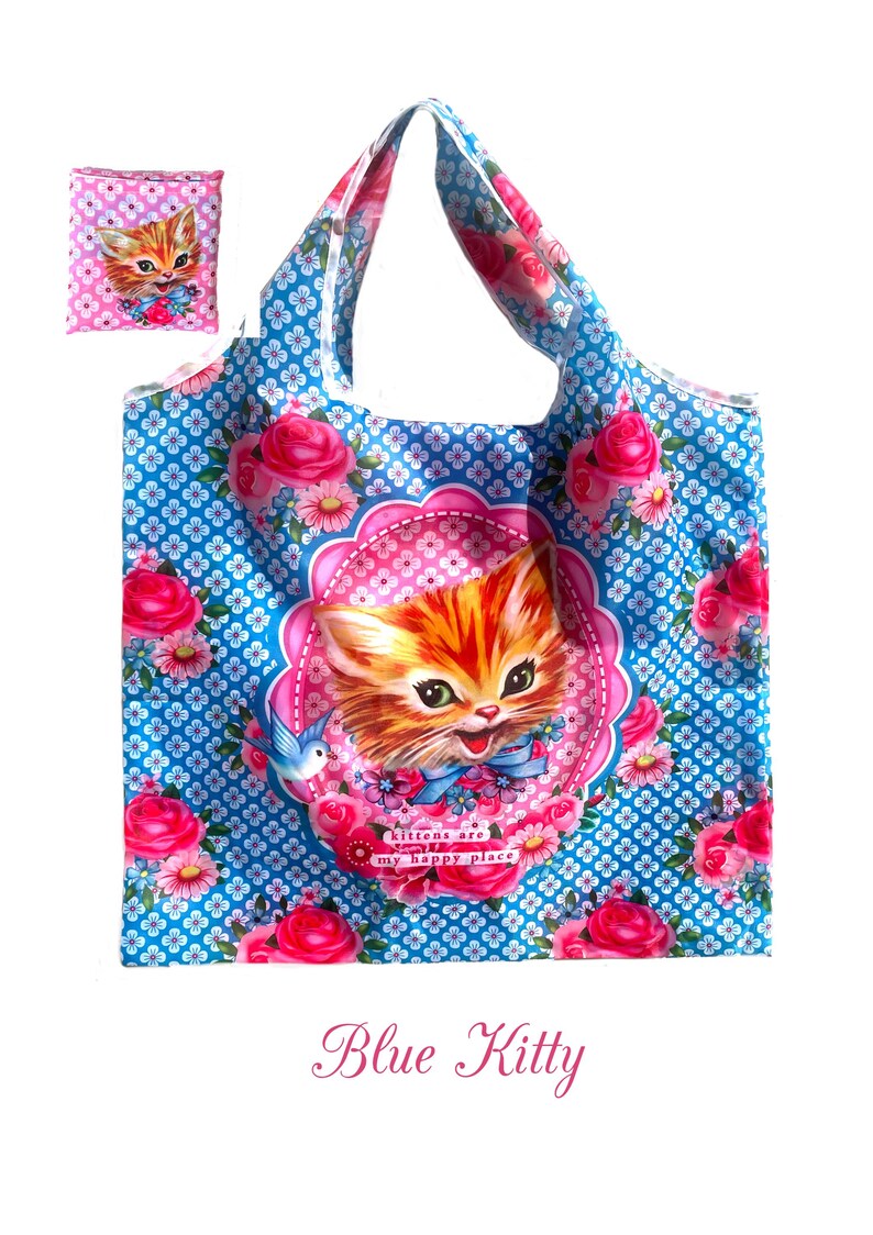 Puede incluir: Bolso tote azul con dise&ntilde;o floral y gatito. El bolso presenta un fondo azul con un patr&oacute;n floral blanco repetido y rosas rosas. Un gran gato atigrado naranja est&aacute; centrado en el bolso, rodeado por un marco rosa y las palabras "kittens are my happy place."