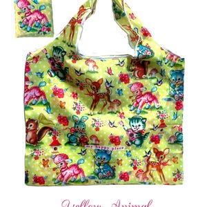 Puede incluir: Un bolso tote amarillo y una bolsa a juego con un estampado de animales, flores y mariposas de estilo vintage. El dise&ntilde;o incluye ciervos, corderos, gatos y osos. Tambi&eacute;n se ven las palabras "my happy place".