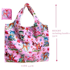Puede incluir: Un bolso tote rosa con un estampado caprichoso de ciervos, osos, gatos y otros animales, junto con flores y setas. El bolso mide 44 cm de ancho y 55 cm de alto, asas incluidas. Se incluye una bolsa plegada a juego. Las palabras "my happy place" est&aacute;n impresas en el bolso.