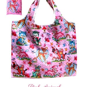 Puede incluir: Bolso tote rosa y bolsa a juego con un estampado de animales de dibujos animados, incluyendo ciervos y osos, sobre un fondo rosa con flores y mariposas. El texto "my happy place" tambi&eacute;n es visible.