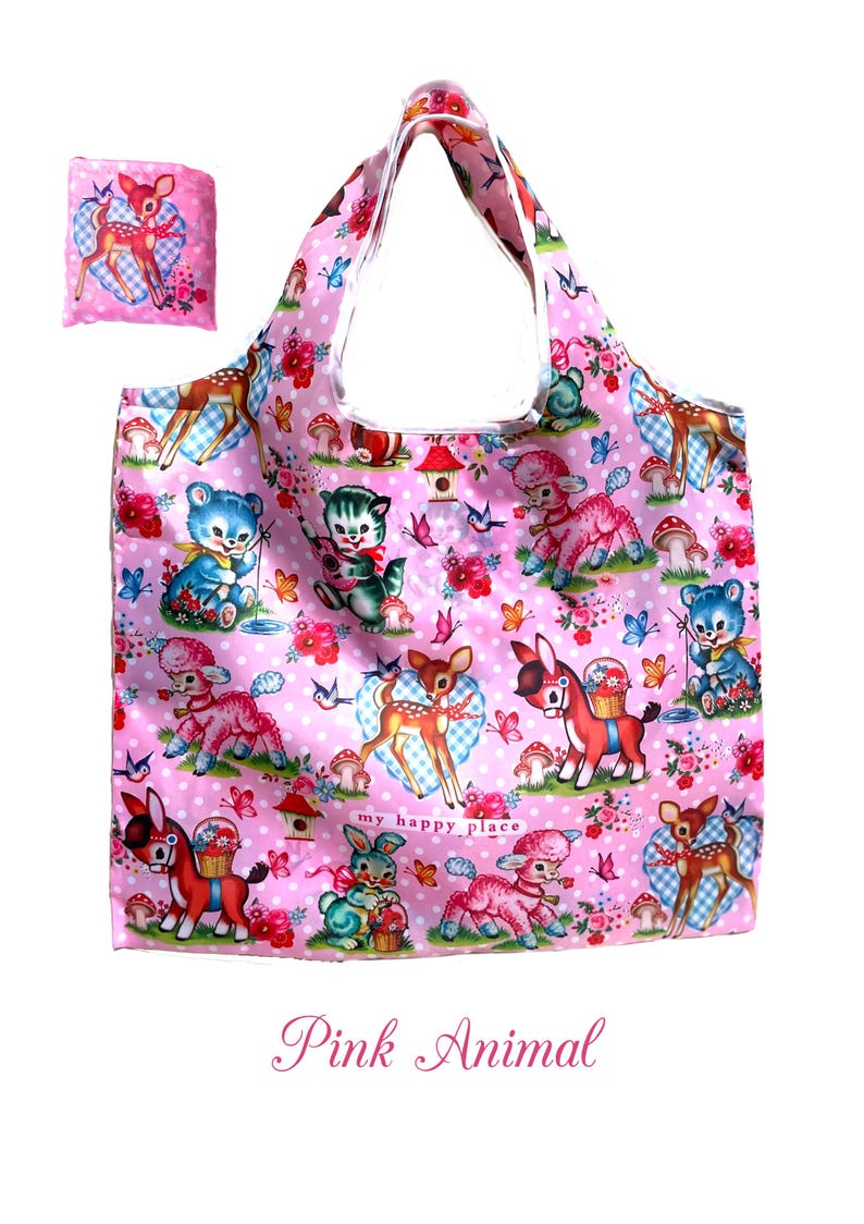 Puede incluir: Bolso tote rosa y bolsa a juego con un estampado de animales de dibujos animados, incluyendo ciervos y osos, sobre un fondo rosa con flores y mariposas. El texto "my happy place" tambi&eacute;n es visible.