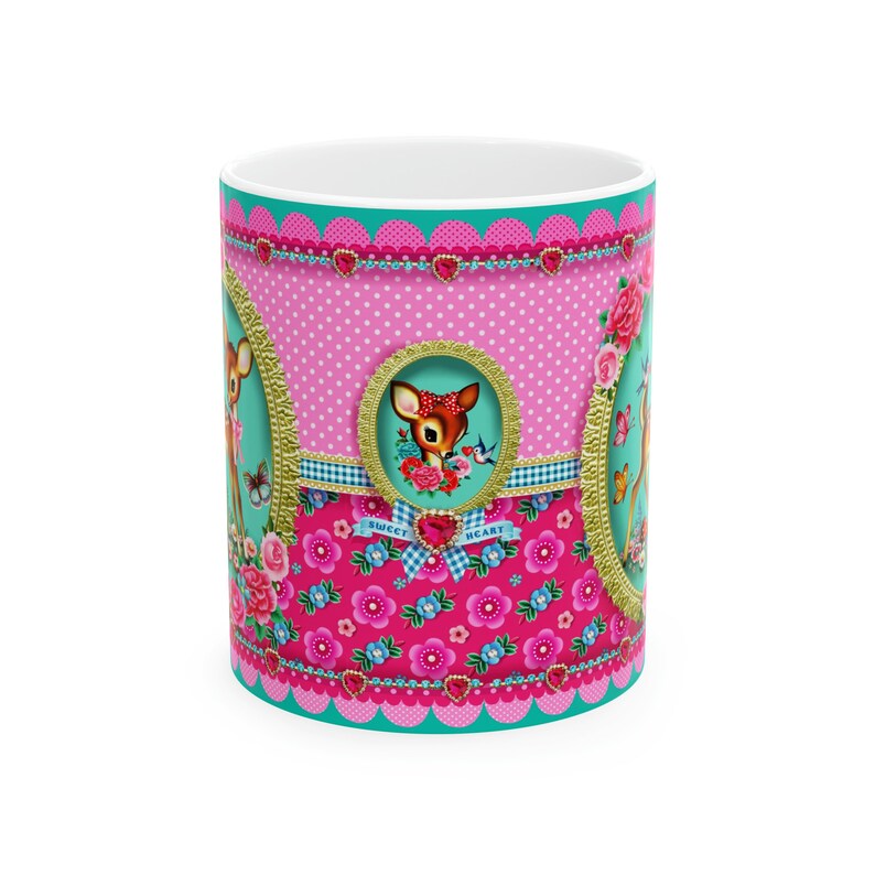 May include: A pink and turquoise ceramic mug with a floral pattern and a deer design. The mug has the words "Sweet Heart" on it.