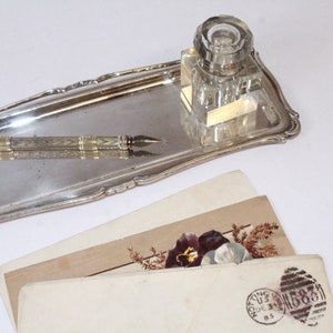 Pluma y lápiz antiguos con tintero, bandeja y carta.