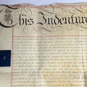 Könnte beinhalten: Ein antikes Dokument mit kunstvoller Kalligraphie und einem königlichen Wappen. Das Dokument mit dem Titel "his Indenture" weist eine aufwendige Schrift und rote Randlinien auf. Ein blaues Quadrat mit einem kleinen Bild befindet sich unten links.