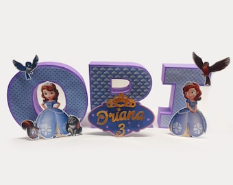 May include: Purple wooden letters spelling "ORI" with a princess character and a bird on each letter. A sign with the name "Ariana" and the number "3" is in front of the letter "R".